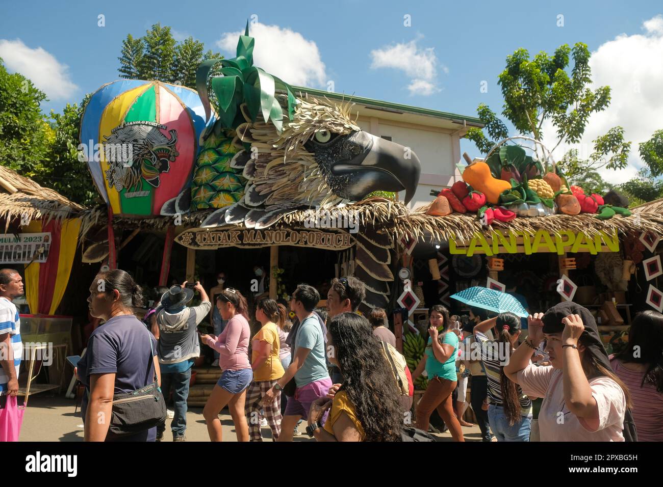 Città di Malaybalay, Filippine - la gente cammina su una strada trafficata con le capanne decorate del nipa come i depositi pop-up che vendono i beni locali al festival di Kaamulan in Bukidnon. Foto Stock