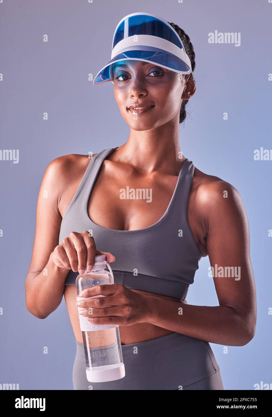 Guardate cosa può fare una sana quantità di disciplina. Studio shot di una giovane donna in forma che beve acqua in bottiglia su uno sfondo grigio. Foto Stock