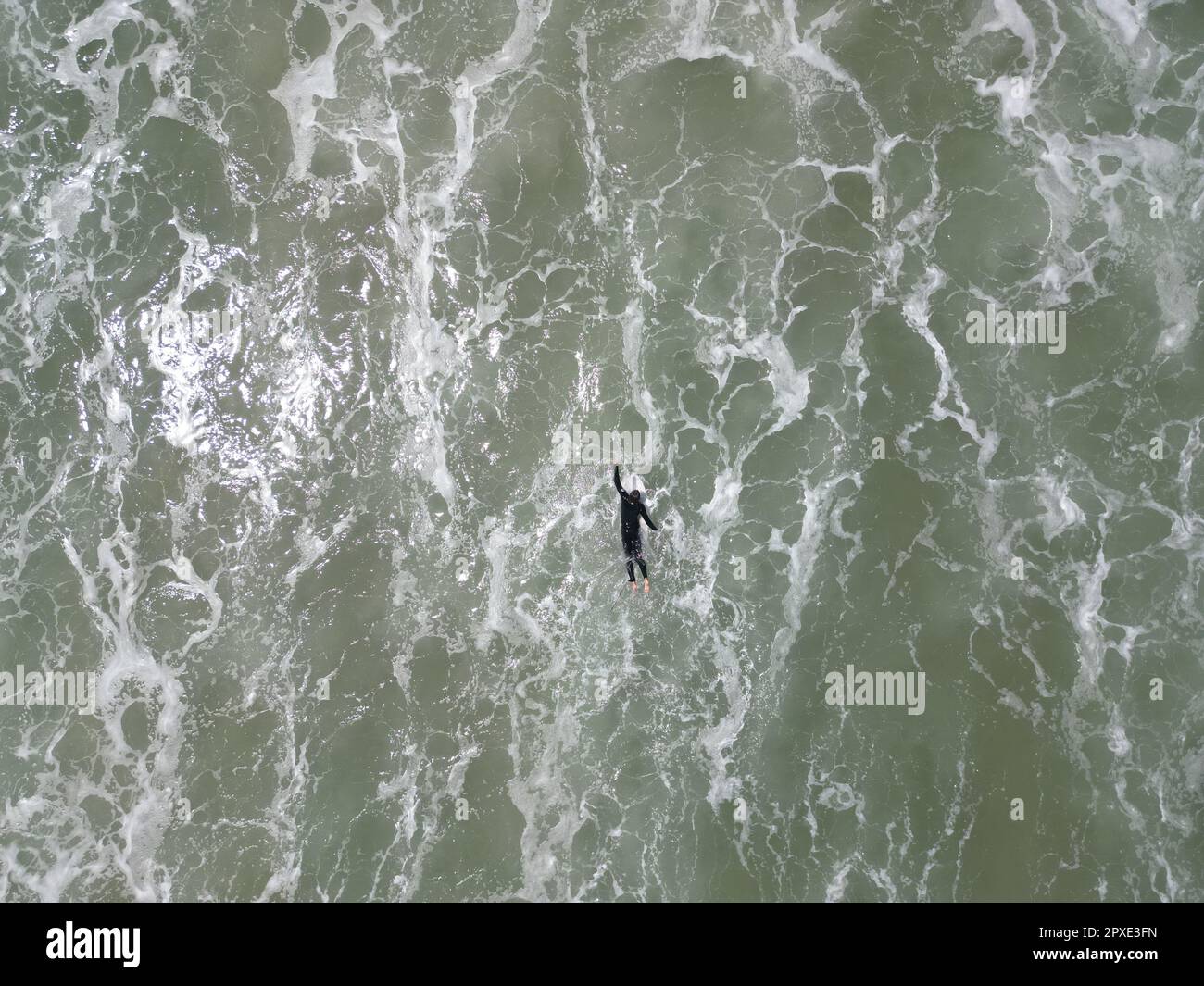 Un surfista maschile si alza in cima a un'onda con una tavola da surf, dimostrando una padronanza dello sport Foto Stock