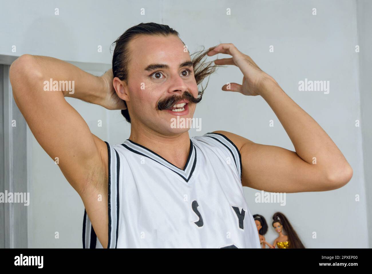 Latina giovane di etnia argentina e di genere non binario indignato nella sua stanza legando i capelli, in piedi parlando e lamentandosi. Foto Stock