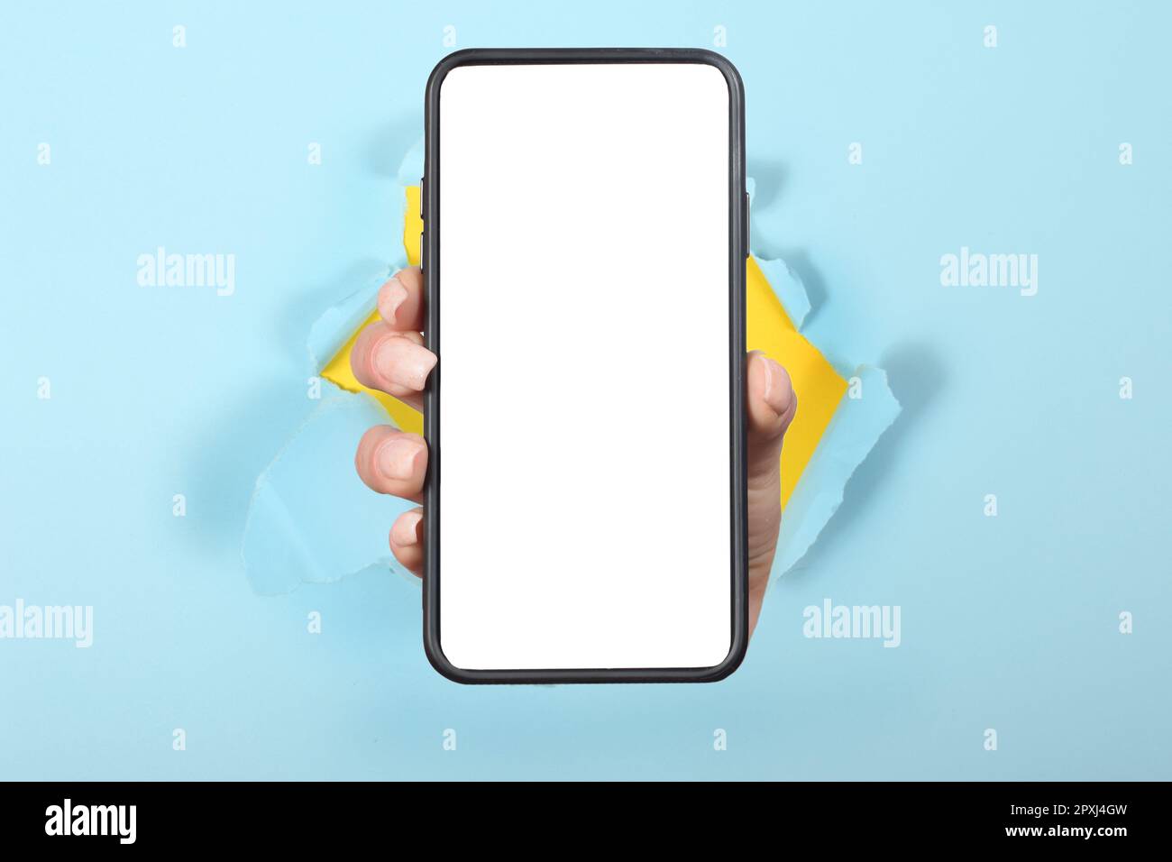 tenere lo smartphone con lo schermo vuoto bianco che mostra il dispositivo vicino alla fotocamera che si infrange il foglio di carta blu Foto Stock