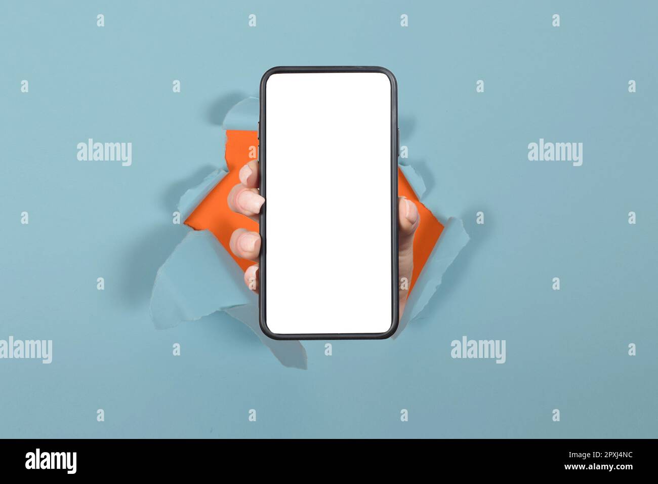 tenere lo smartphone con lo schermo vuoto bianco che mostra il dispositivo vicino alla fotocamera che si infrange il foglio di carta blu Foto Stock