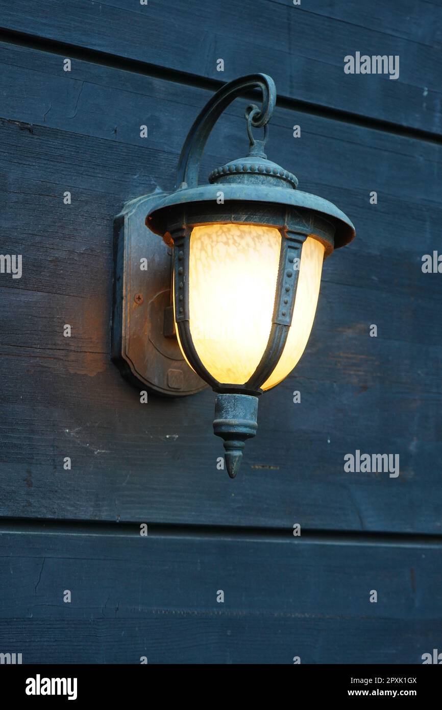 Lampada illuminata che diffonde una calda luce gialla sulle pareti di legno in un ristorante Foto Stock
