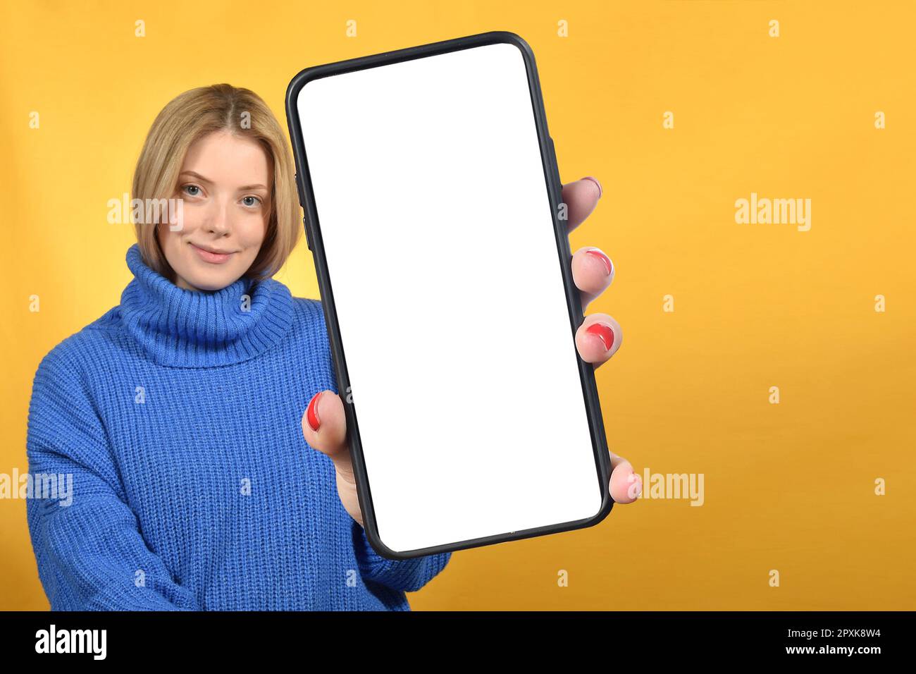 Smartphone con supporto in ladie millennial positivo con schermo bianco su sfondo colorato dello studio Foto Stock