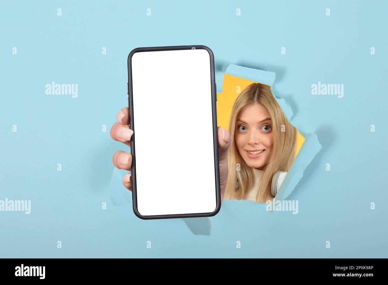 Smartphone con supporto in ladie millennial positivo con schermo bianco su sfondo colorato dello studio Foto Stock