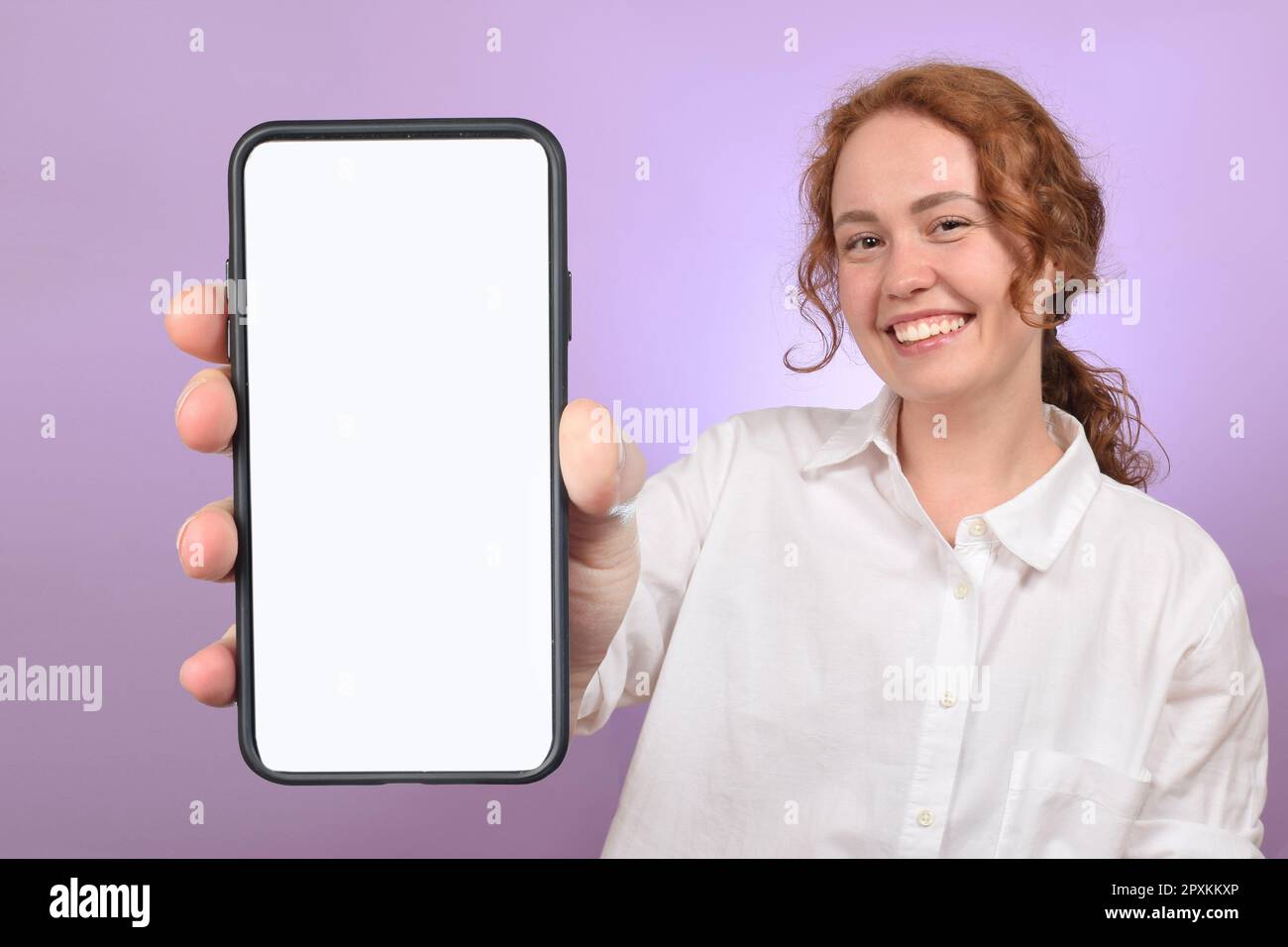 Smartphone con supporto in ladie millennial positivo con schermo bianco su sfondo colorato dello studio Foto Stock