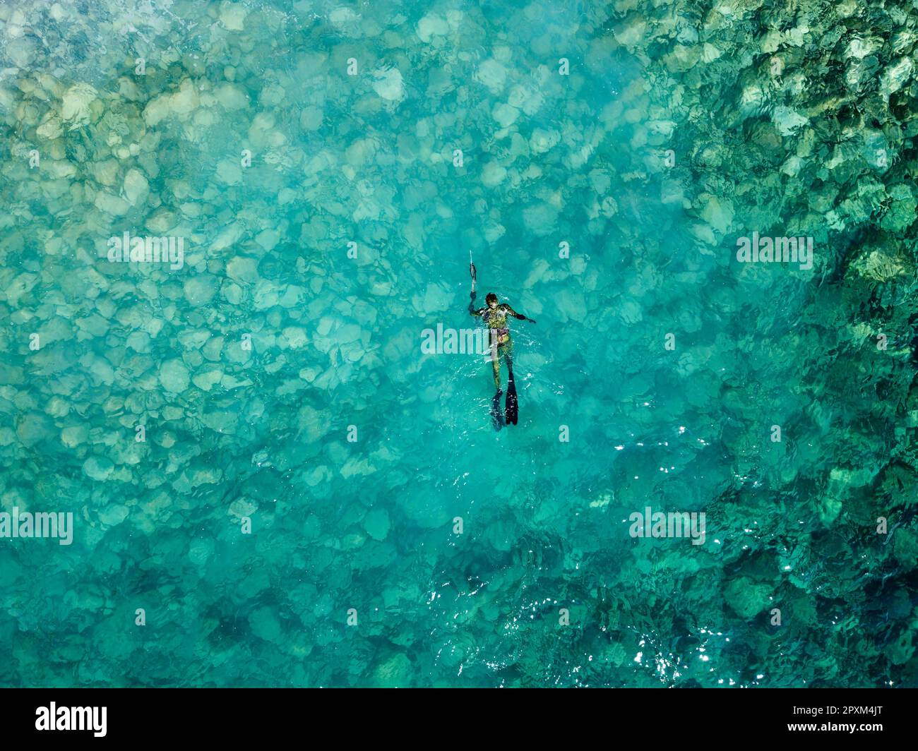 Vista aerea del drone di una persona che fa pesca di spearfishing su acqua blu cristallo. Pesca ricreativa e attività estive. Estate. Foto Stock