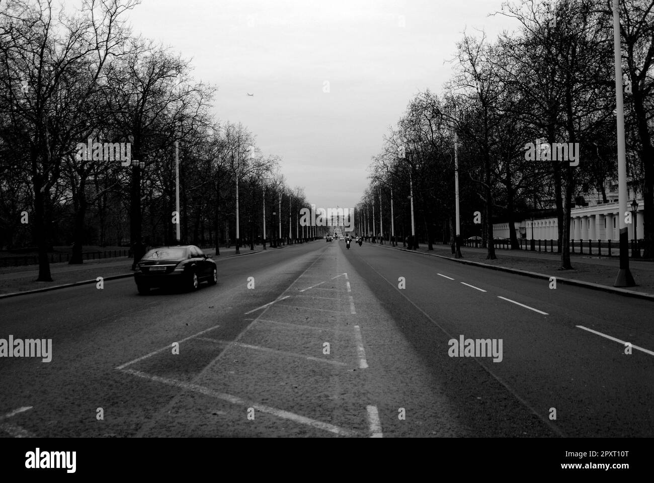 Strada cittadina con auto e moto che arriva con palazzo alla fine della strada Foto Stock