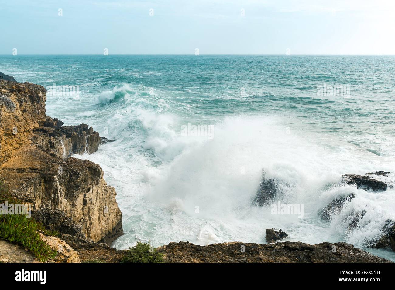 Costa con l'oceano atlantico a Cascais, Portogallo. Onde sulla riva e colline rocciose Foto Stock