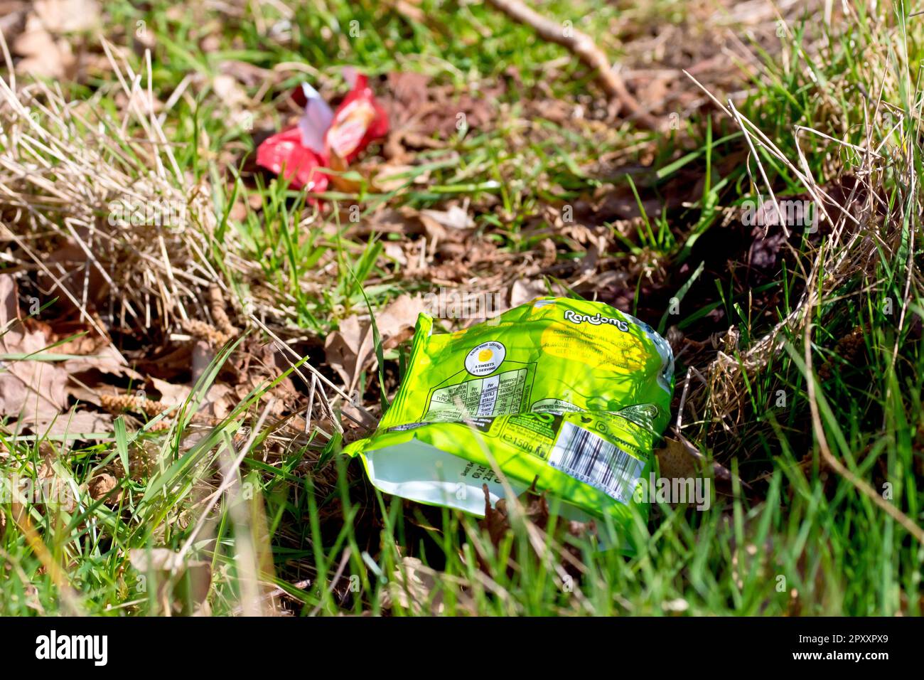 Primo piano di alcuni pacchetti o involucri dolciari o dolci scartati sconsideratamente sul bordo di un sentiero di campagna. Foto Stock