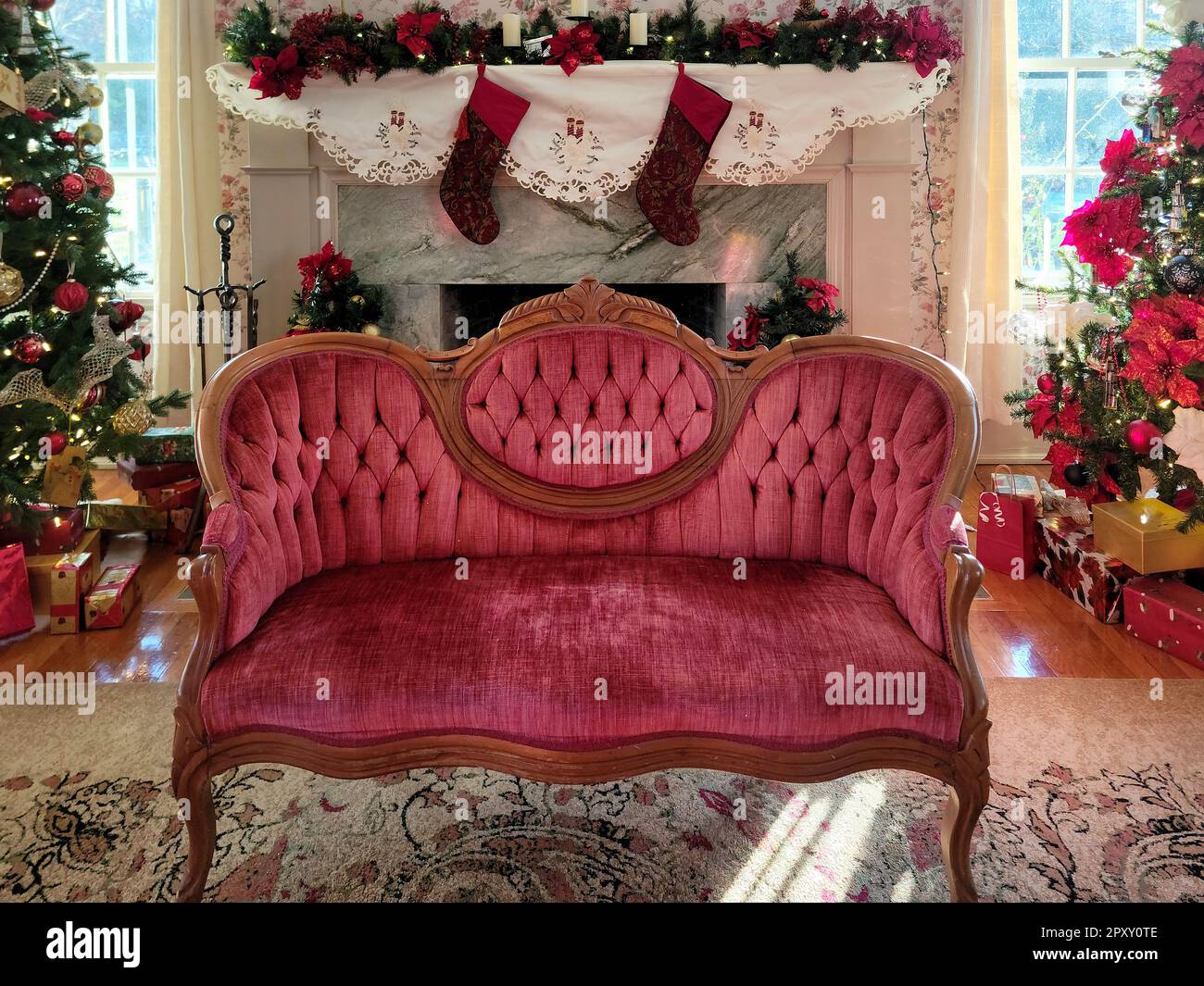 Divano Vittoriano di velluto rosso di fronte a un camino con calze di Natale Foto Stock