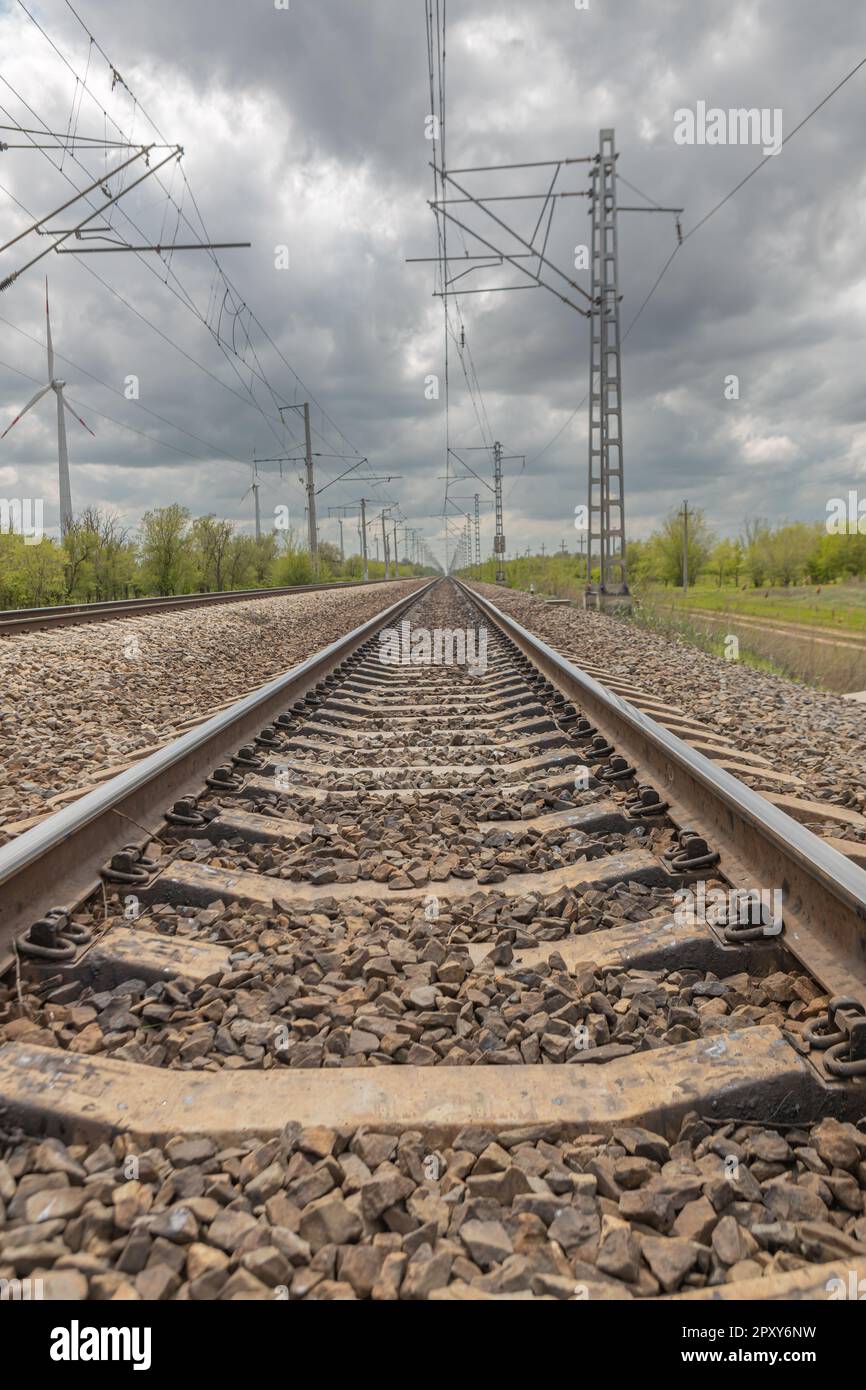 in primavera, i binari della ferrovia vanno in lontananza, cielo blu con nuvole bianche Foto Stock