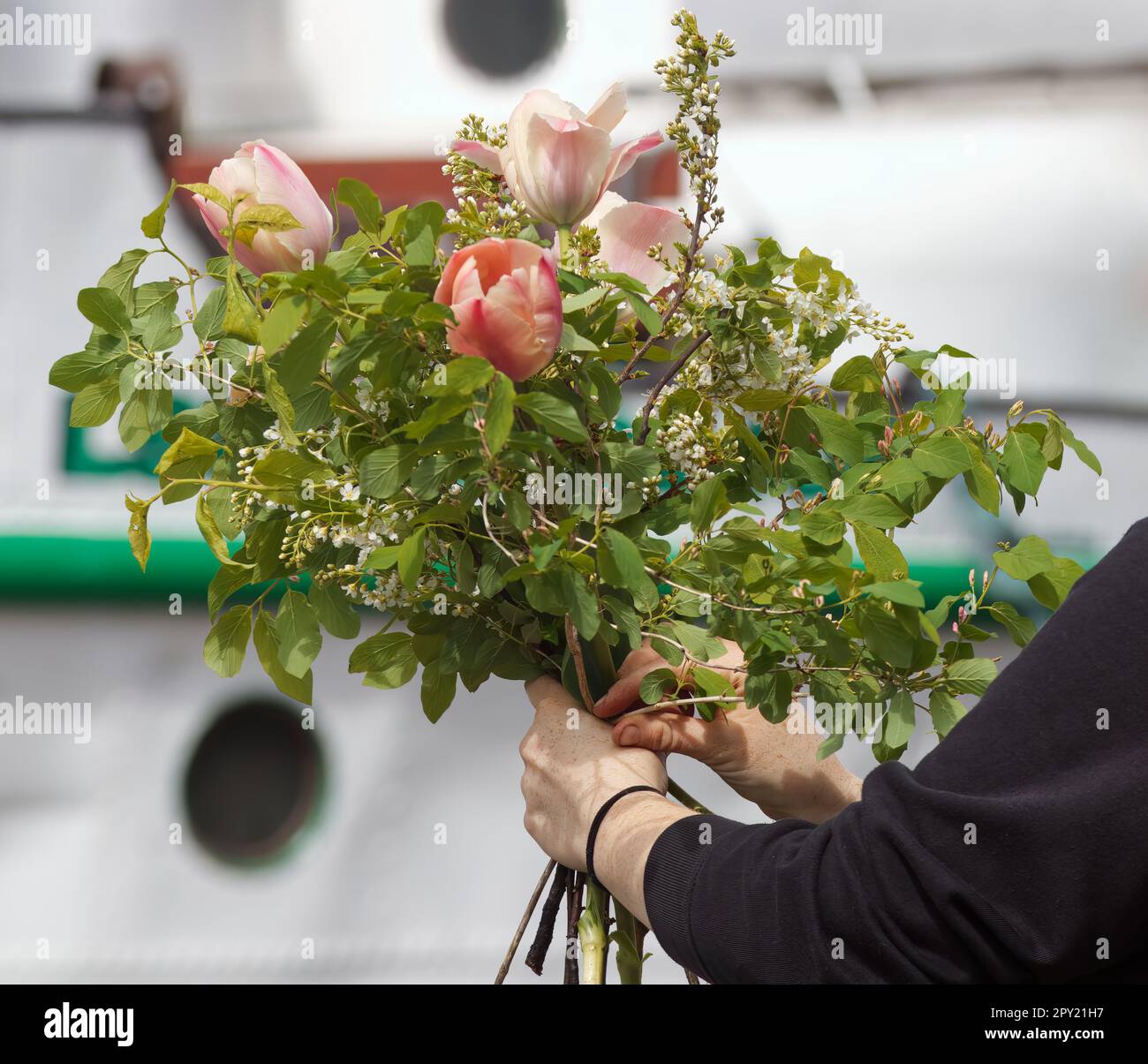 Un fiorista lega un bouquet ad un mercato agricolo, una mano di donna che tiene un bouquet legato grande. Foto Stock