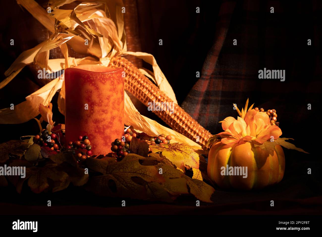 Foto di vita morta con candele e decorazioni di raccolto, zucca e pannocchie di mais Foto Stock