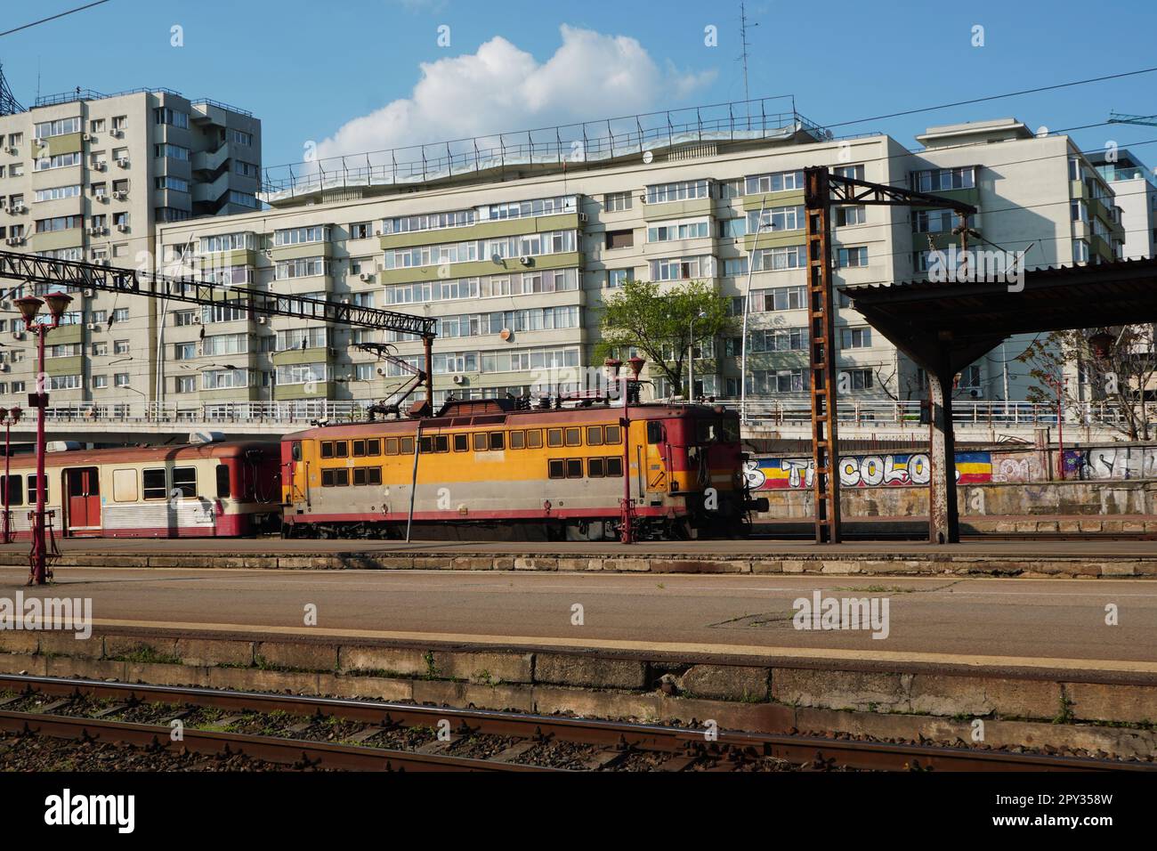 Treno datato di proprietà di una piccola compagnia di trasporto passeggeri che arriva alla stazione ferroviaria nord di Bucarest in una giornata di sole Foto Stock