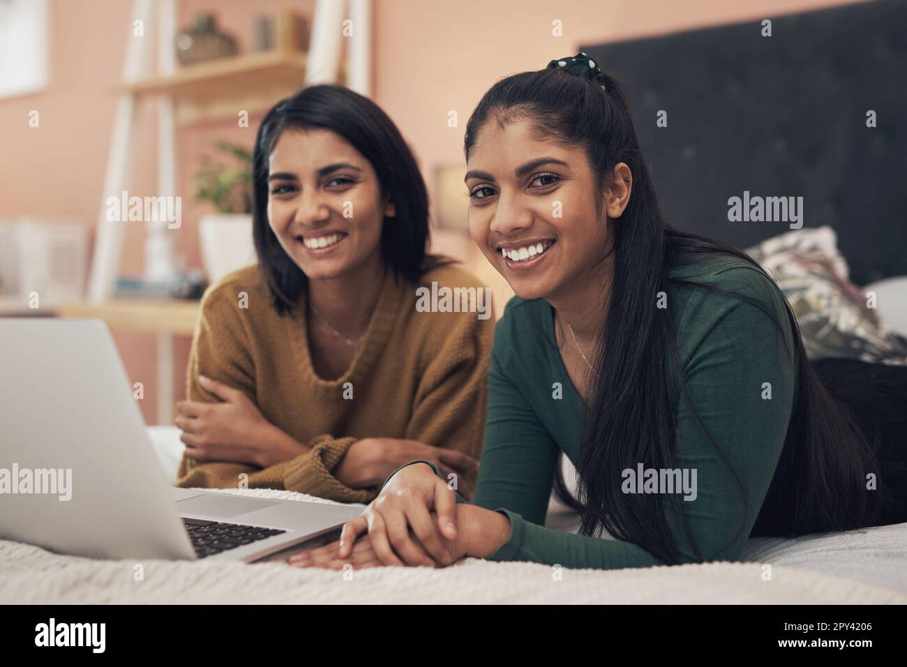 Troviamo sempre qualcosa per tenerci intrattenuti online. due giovani donne che usano un computer portatile mentre si sdraiano insieme su un letto. Foto Stock
