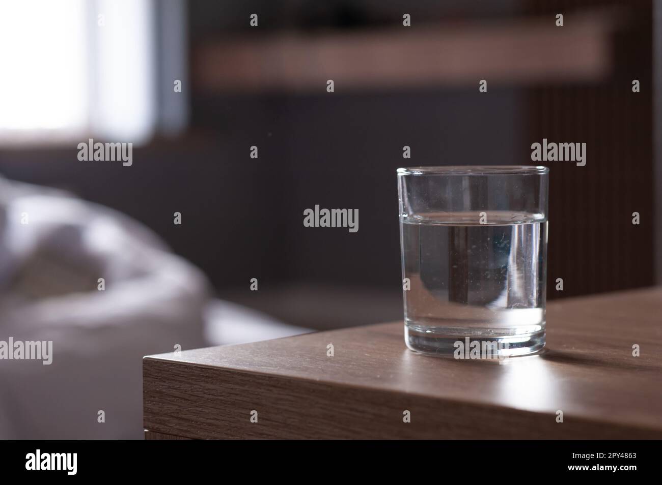 Bicchiere d'acqua sul tavolo in legno in camera. Spazio per il testo Foto Stock