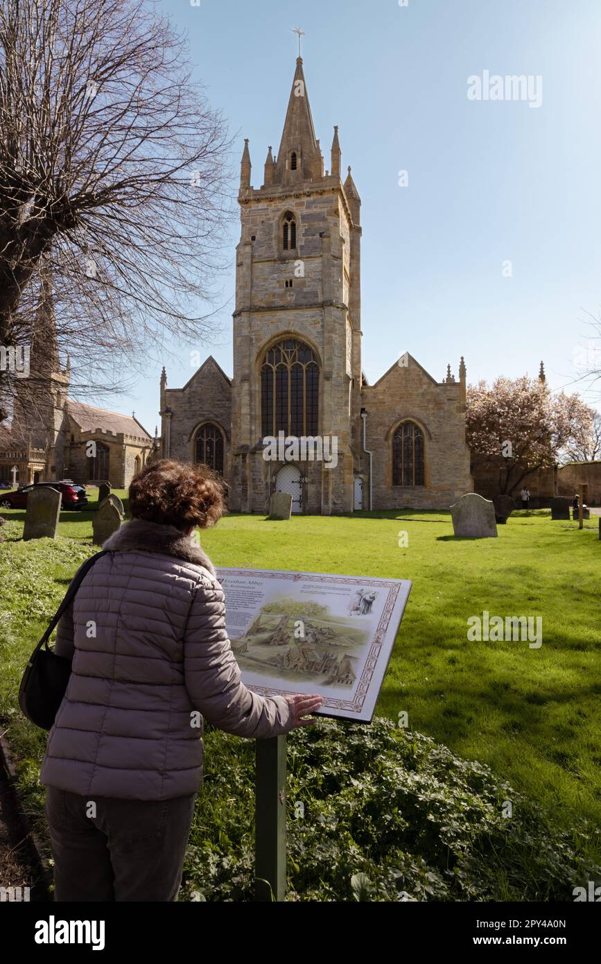 Una donna che legge una bacheca di informazioni di fronte alla Chiesa di San Lorenzo, Evesham. La chiesa, ora ridondante, si trova accanto alla Chiesa di tutti i Santi. Foto Stock