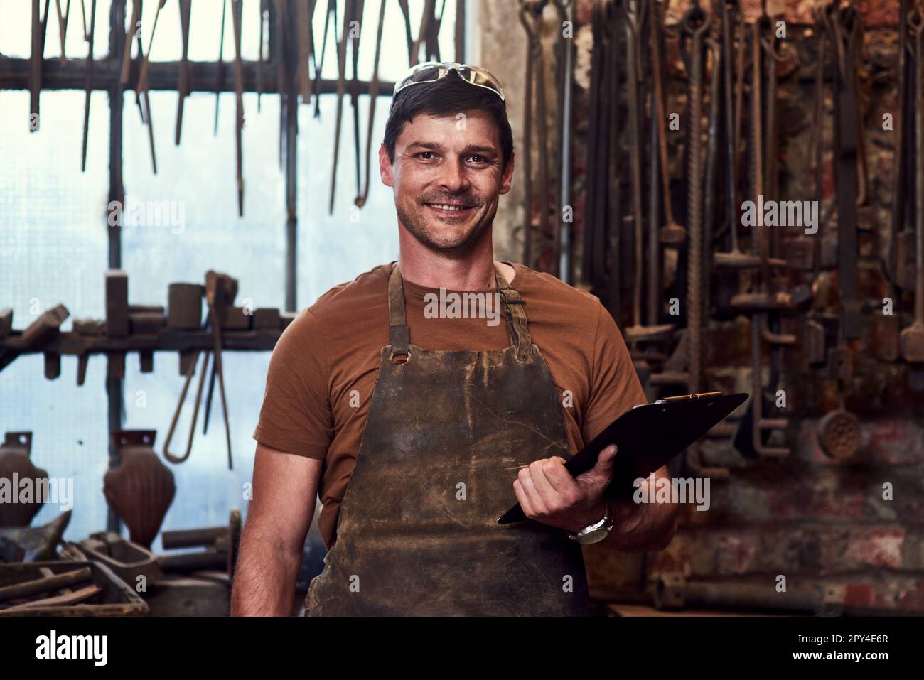 In officina sono necessari anche strumenti e dispositivi intelligenti. Ritratto di un bel giovane artigiano utilizzando un tablet digitale mentre lavora all'interno di un metallo Foto Stock