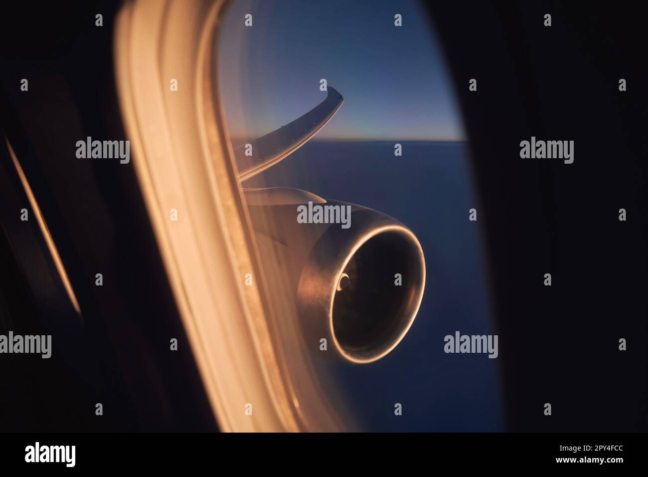 Vista dalla finestra dell'aereo durante il volo sopra le nuvole all'alba. Attenzione selettiva al motore a reazione e all'ala dell'aeromobile. Foto Stock
