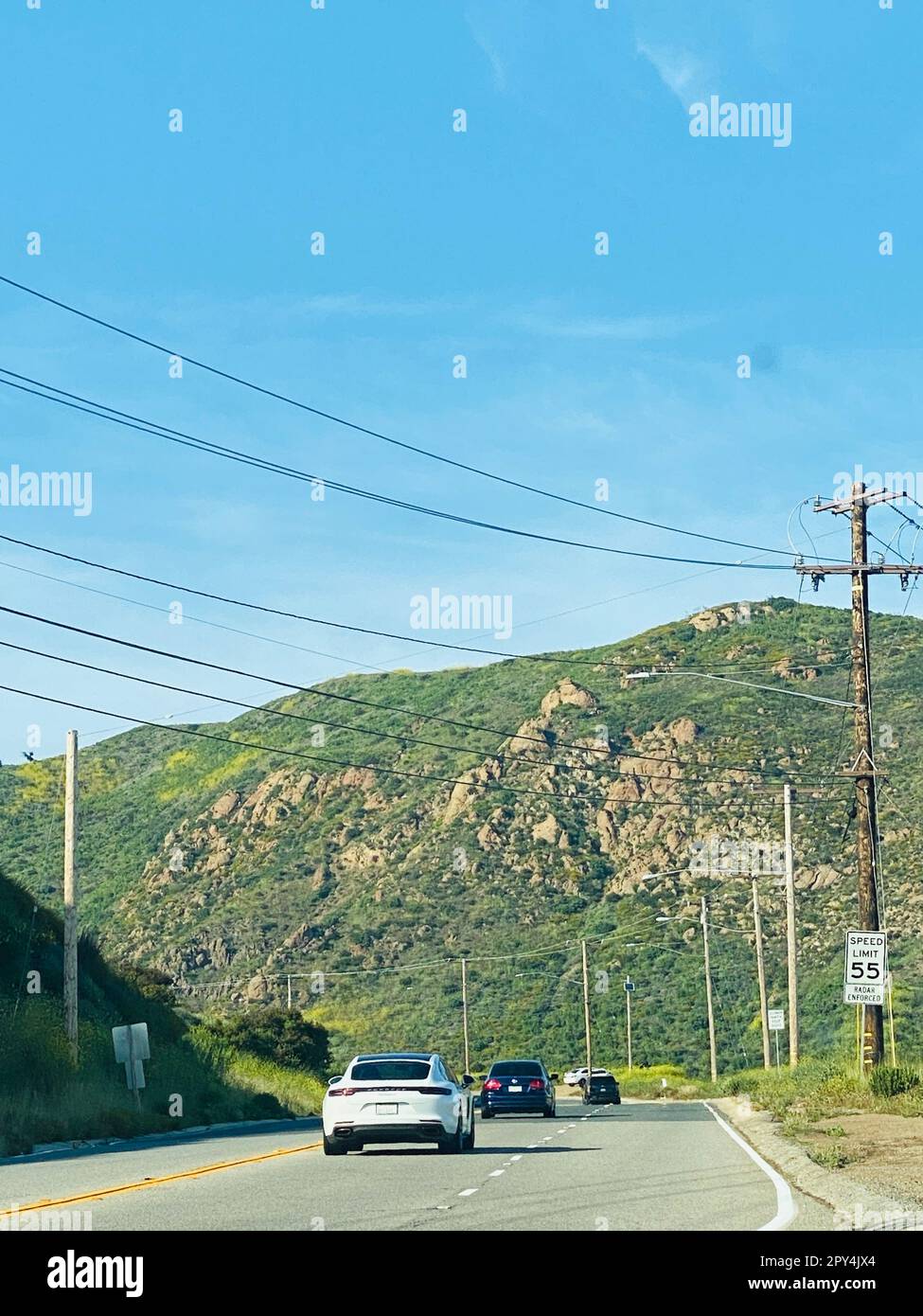 Le vetture che percorrono una strada tortuosa, con un segnale di limite di velocità visibile sul lato del percorso Foto Stock