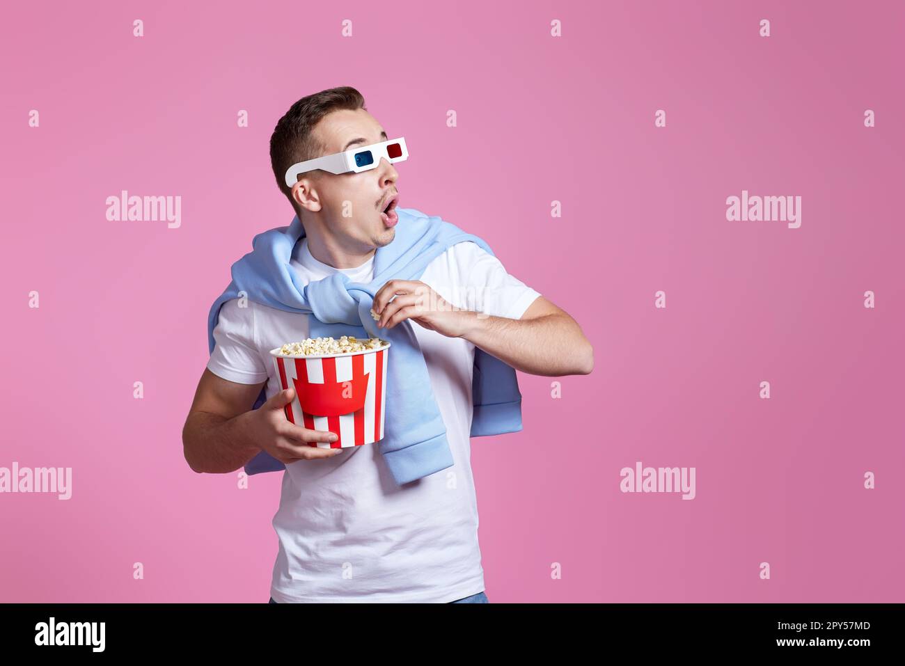 uomo spaventato in 3d bicchieri che tengono un secchio di popcorn Foto Stock