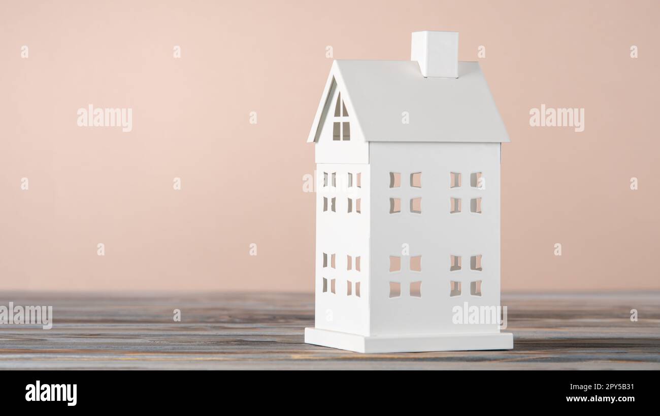 Modello giocattolo bianco della casa in cartone su tavolo grigio. Investimenti immobiliari. Costo dell'alloggio, pagamenti assicurativi. Foto Stock
