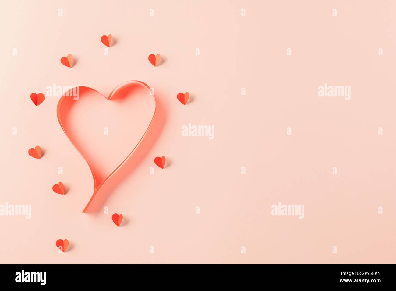 Nastri a forma di cuore ed elementi di carta che tagliano i cuori rossi che volano Foto Stock