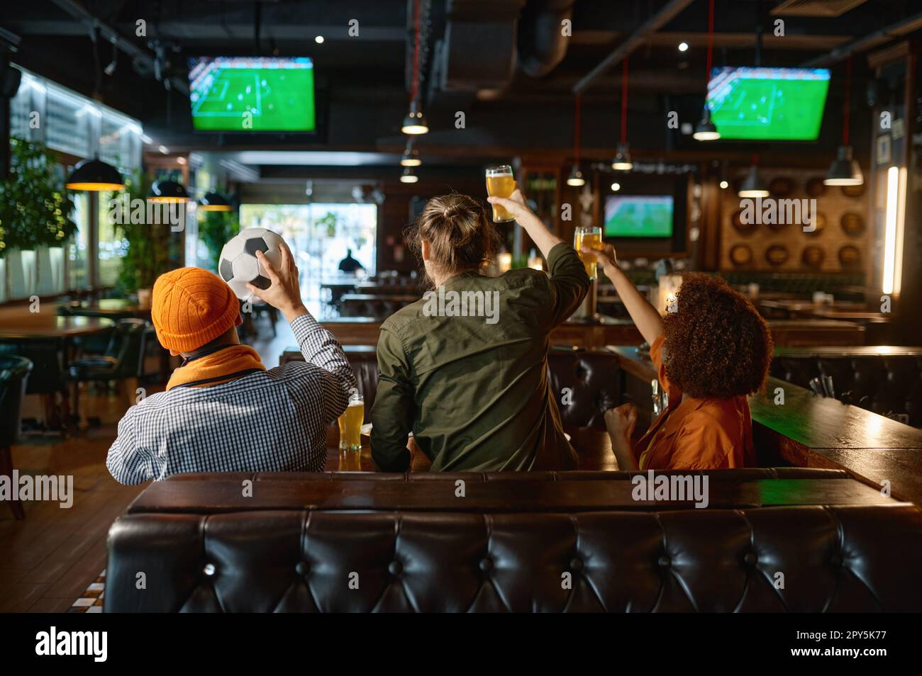 Gruppo di giovani amici che guardano il calcio sullo schermo tv dello sport bar Foto Stock