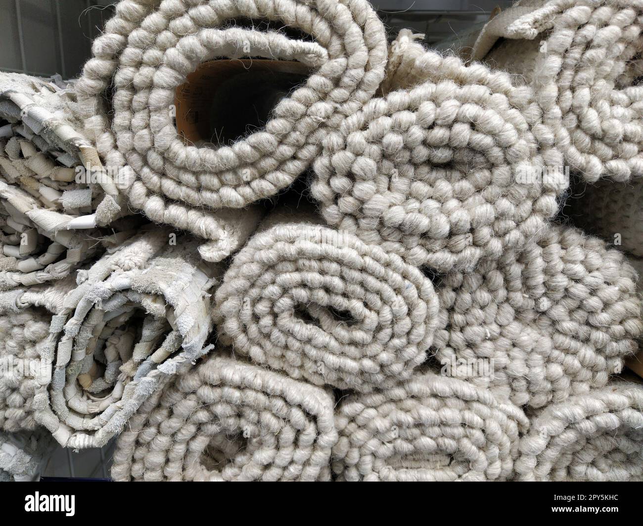 Morbidi tappeti grigi e bianchi piegati in spiedini, rotoli e fasci. Un assortimento di copriletto su uno scaffale. Le coperte sono ben disposte per la vendita. Tessuto sintetico caldo e carnoso Foto Stock