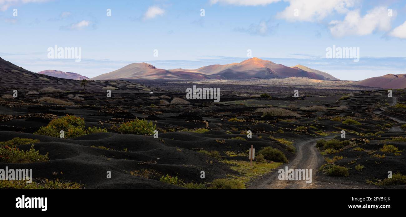 Paesaggio vulcanico nero della regione vinicola di la Geria con vista del Parco Nazionale di Timanfaya a Lanzarote. Popolare attrazione turistica nell'isola di Lanzarote, Isole Canarie, Spagna. Foto Stock