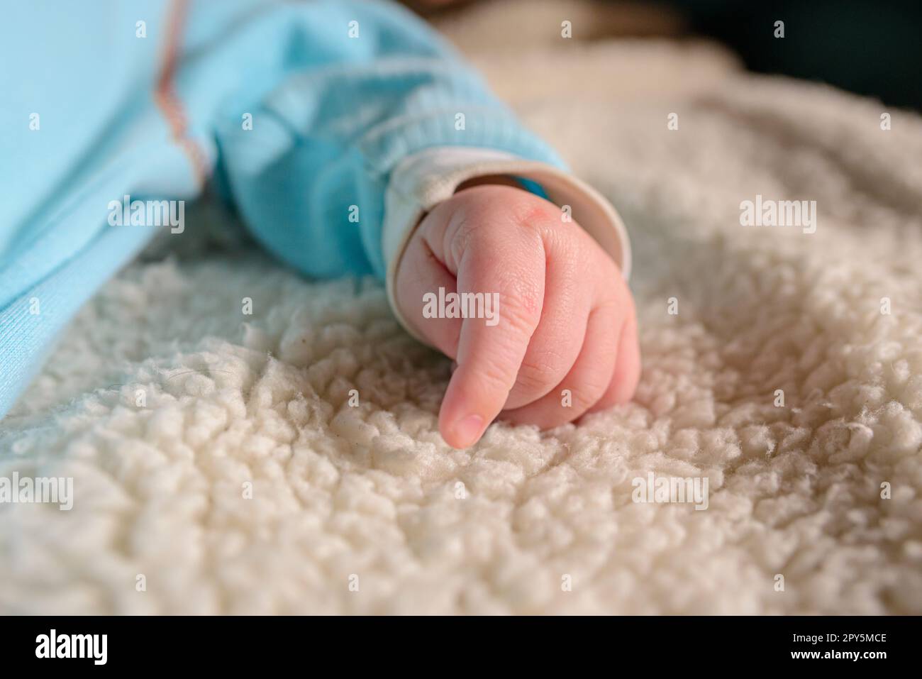 mano con le dita di un neonato europeo bianco su una coperta bianca Foto Stock