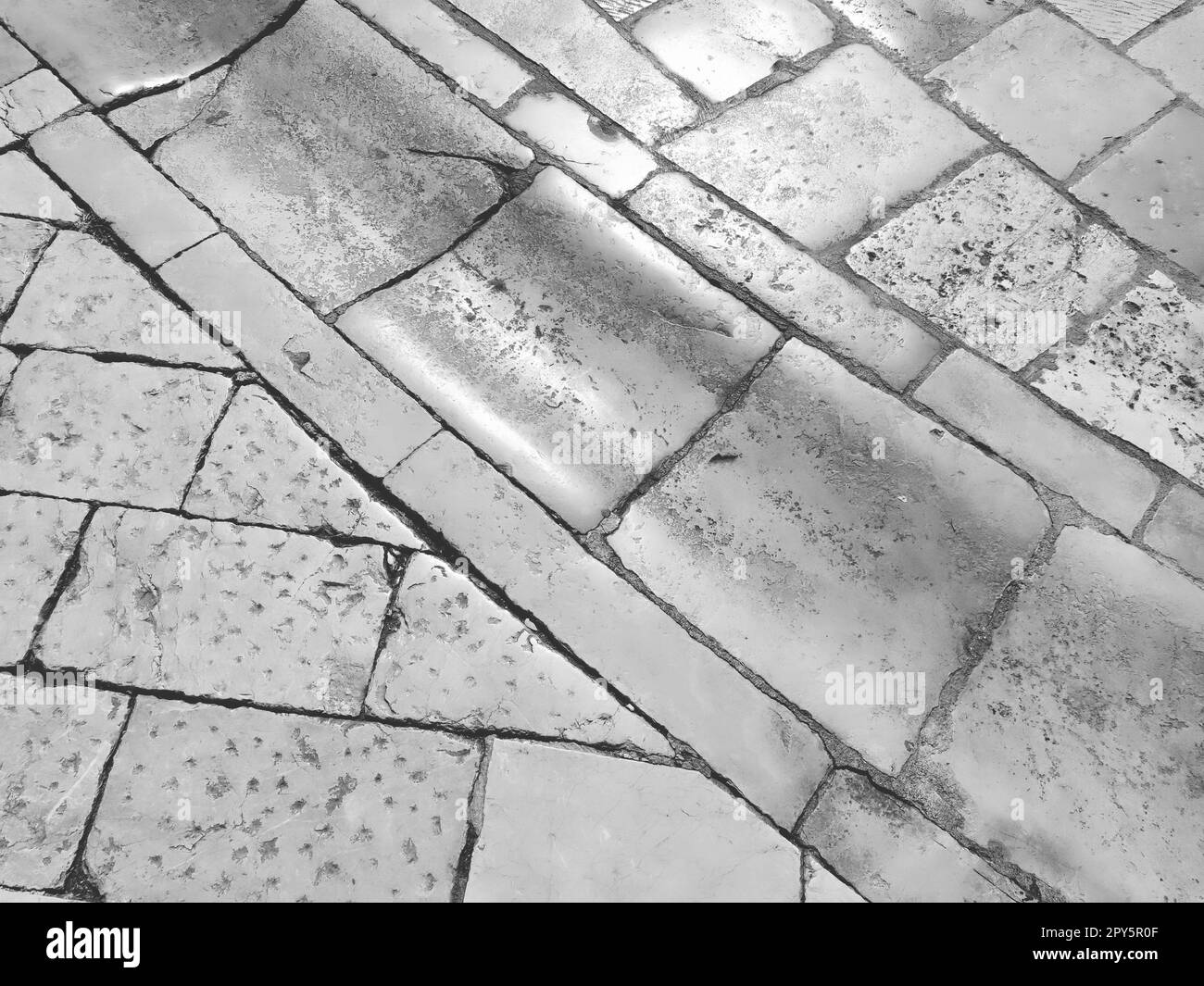 Pavimento in marmo sulla strada, Dubrovnik, Croazia. Mattonelle in muratura antiche blocchi rettangolari. Roccia metamorfica composta da calcite CaCO3. Drenaggio, carbone per l'acqua. Bianco e nero Foto Stock