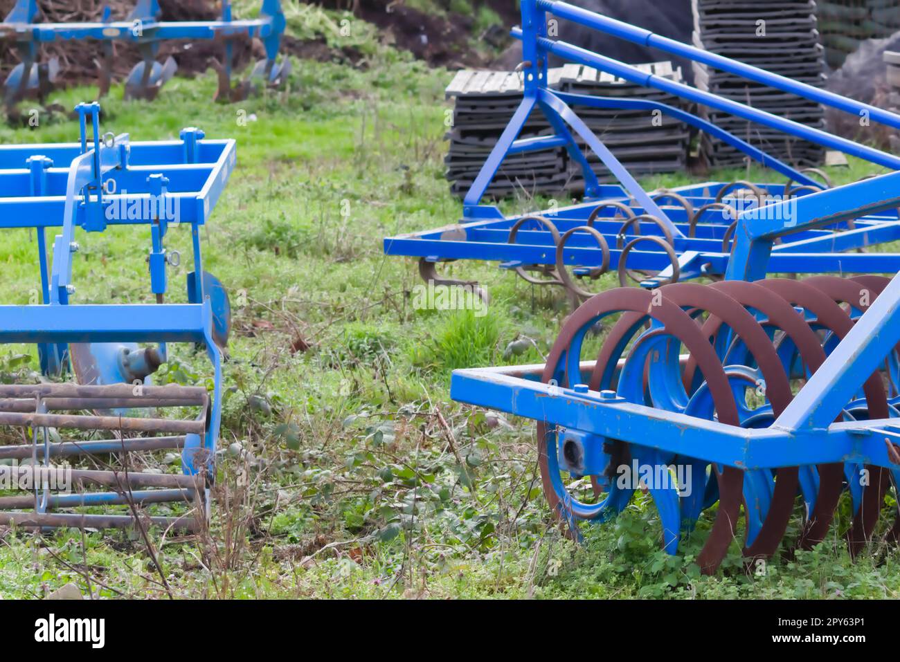 Le attrezzature agricole pesanti blu come l'aratro con dischi in acciaio affilato per la coltivazione agricola su campo con attrezzature trainate da trattore per la preparazione del lavoro sul campo facilitano la meccanizzazione del lavoro agricolo duro Foto Stock