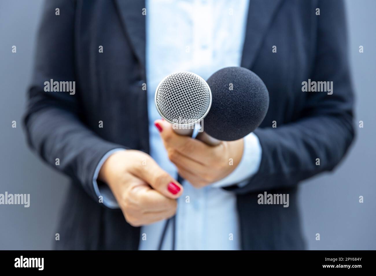 Giornalista televisivo che tiene il microfono durante un'intervista con i media. Concetto giornalistico. Foto Stock