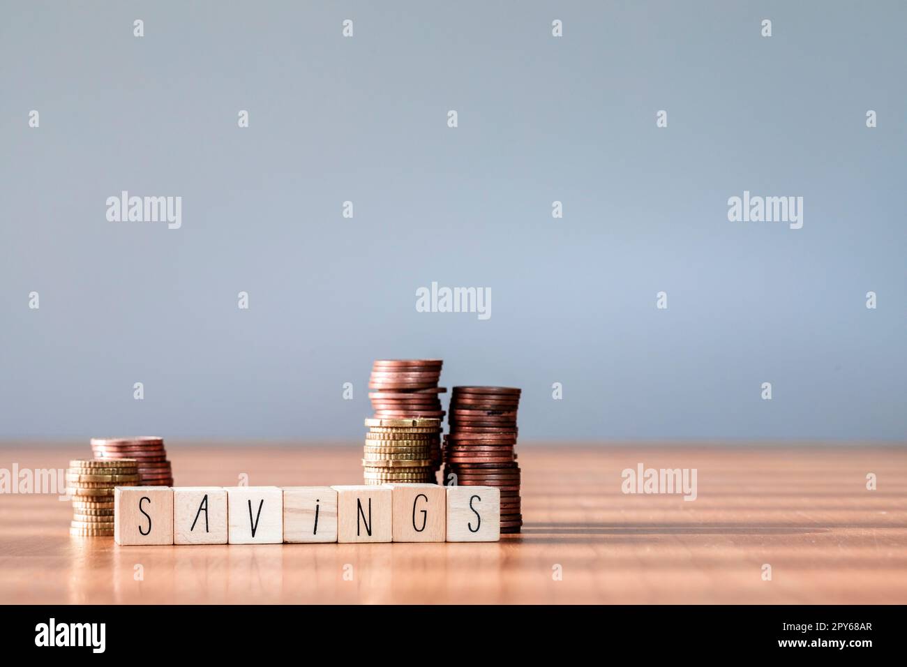 Le monete impilate impilano scatole di legno con testo risparmio per la pianificazione e la crescita, risparmiando denaro per il fondo pensionistico e il concetto di piano futuro. copia spazio Foto Stock