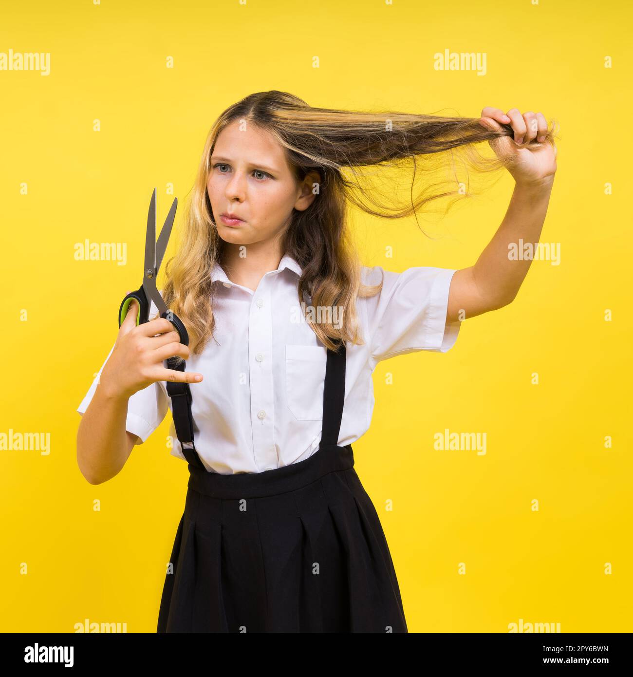 Ragazza scolastica adolescente con forbici, isolata su sfondo giallo. Creatività dei bambini, arti e mestieri. Foto Stock