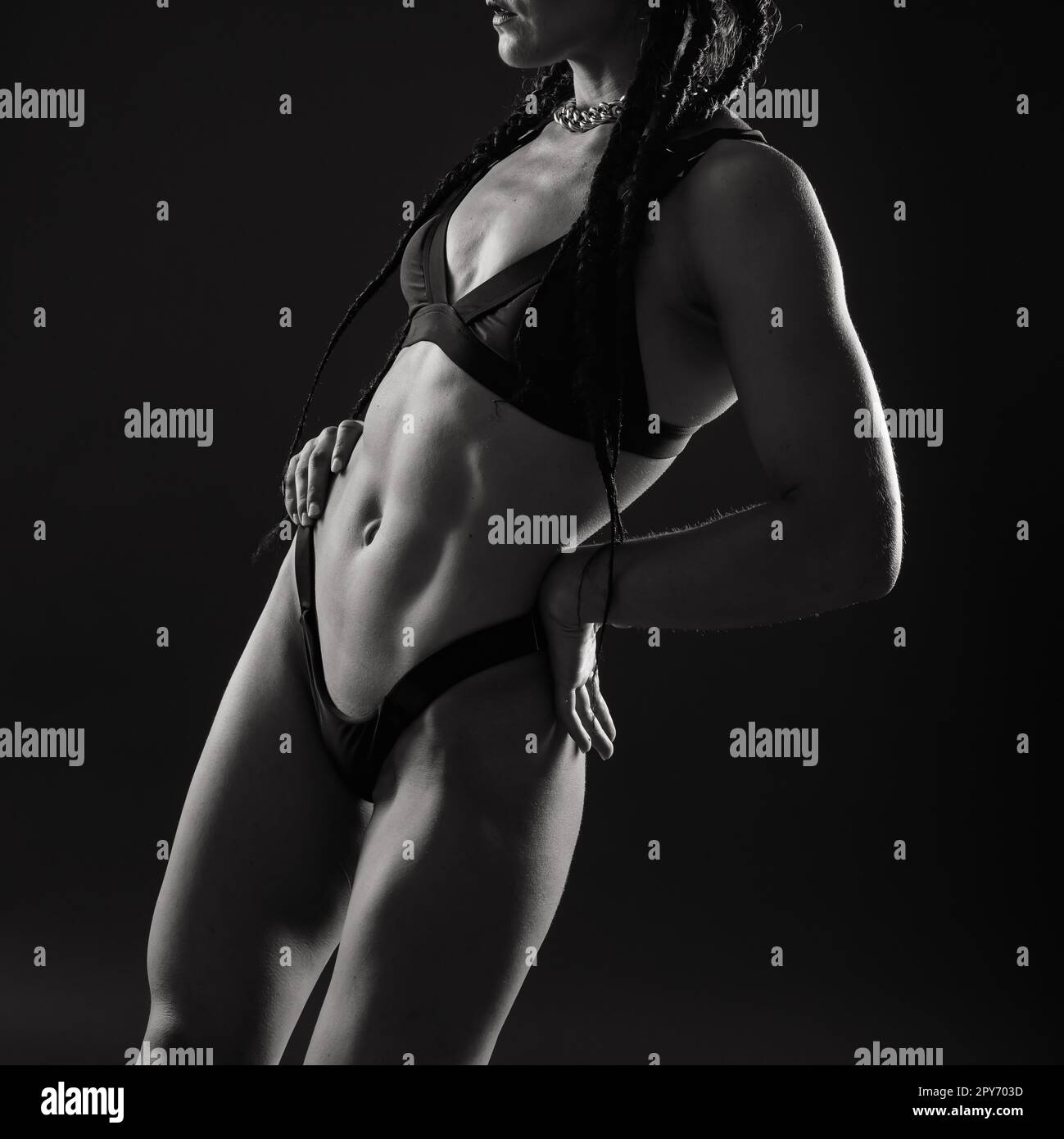 Donna sportiva con grandi muscoli addominali in abbigliamento sportivo nero. Un grande primo piano del corpo sportivo. Foto Stock