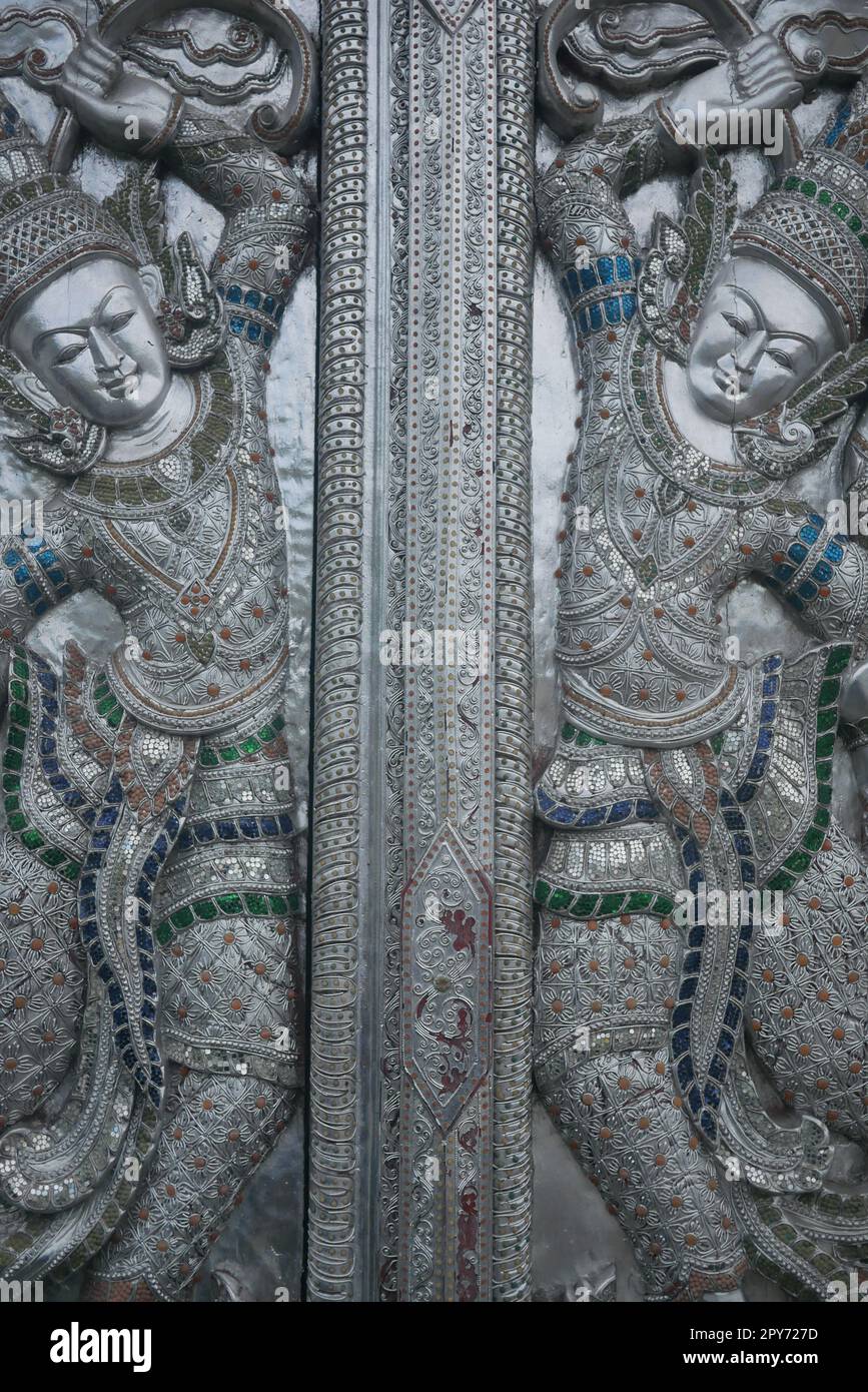 Divinità buddiste gemelle apsara sulla porta del tempio in argento in Thailandia Foto Stock