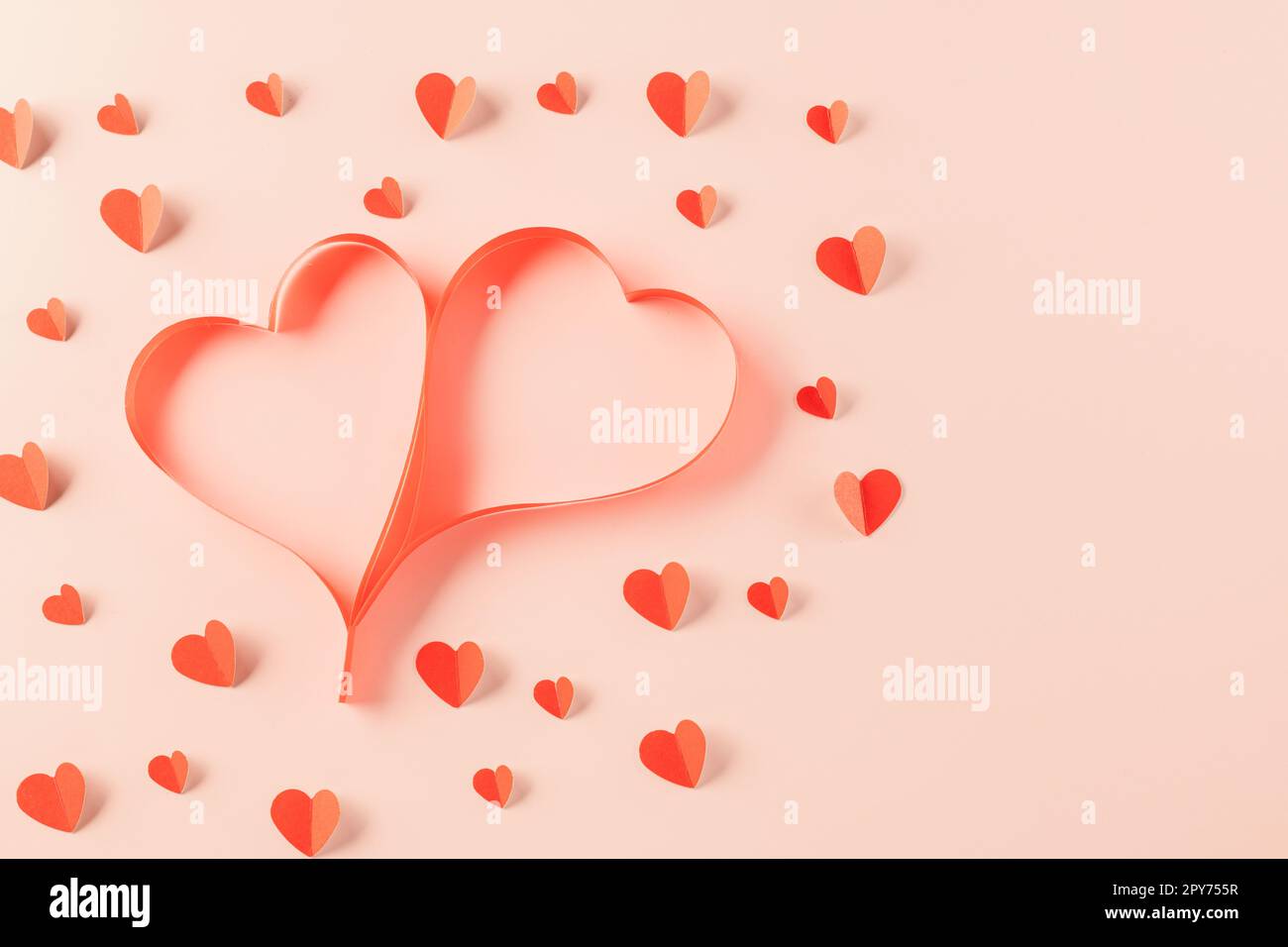 Vista dall'alto piatto di nastri a forma di cuore ed elementi di carta che tagliano cuori rossi che volano Foto Stock