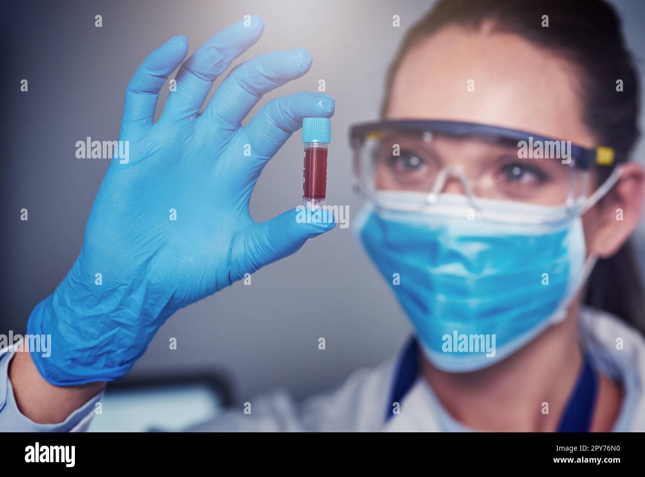 Questo è il risultato finale. Primo piano di uno scienziato femminile irriconoscibile che indossa una maschera protettiva e che tiene un vile di sangue all'interno di un Foto Stock