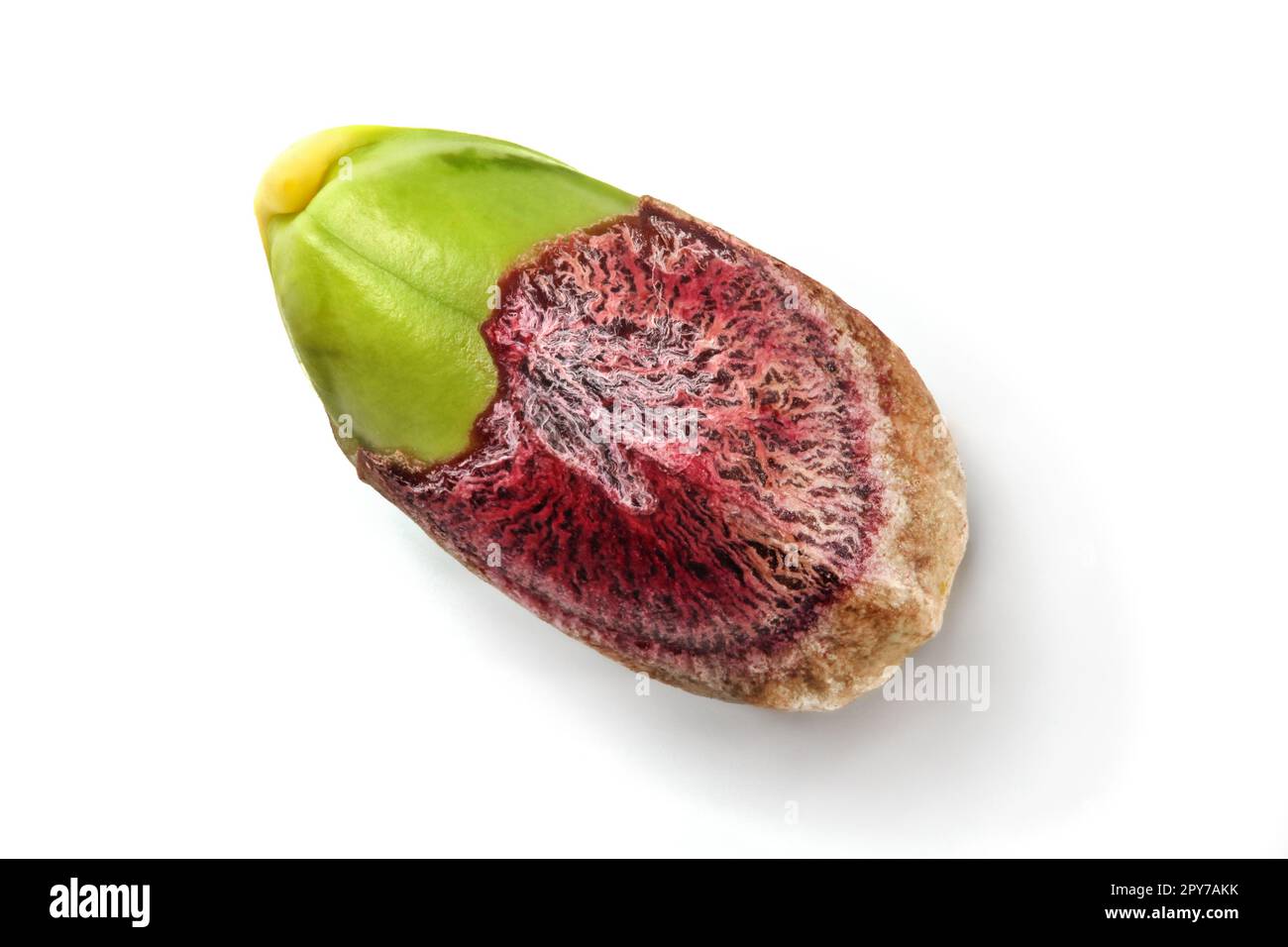 Dettaglio del singolo pistacchio, parziale, pelati, kernel verde visibile sotto la pelle viola, isolato su sfondo bianco. Foto Stock