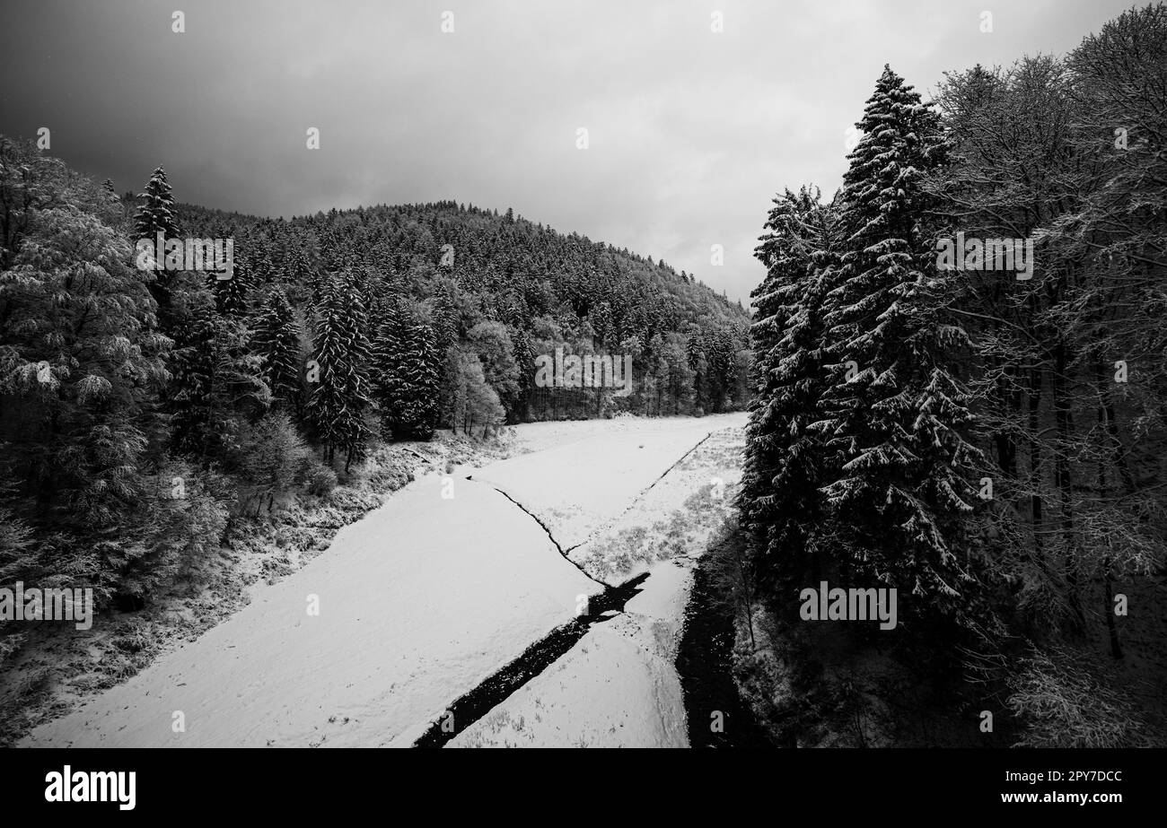 fiume ghiacciato tra la foresta innevata in montagna Foto Stock