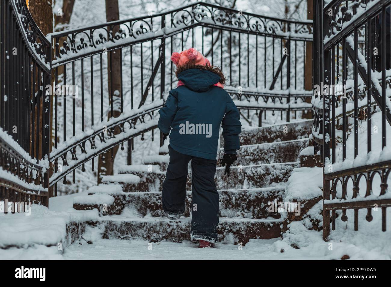 bambino su scale nel parco innevato di montagna Foto Stock