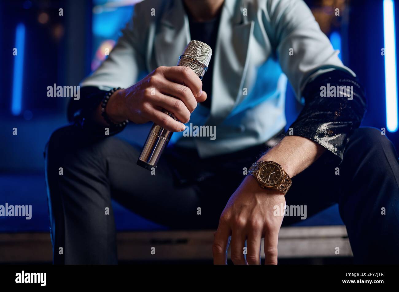 Ripresa ritagliata di un microfono con la mano di un cantante pop maschio Foto Stock