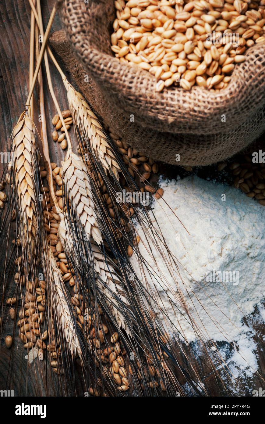 Vintage vita ancora con farine biologiche, tutto il grano in borsa retrò e spighe di grano su tavola in legno rustico. Foto Stock