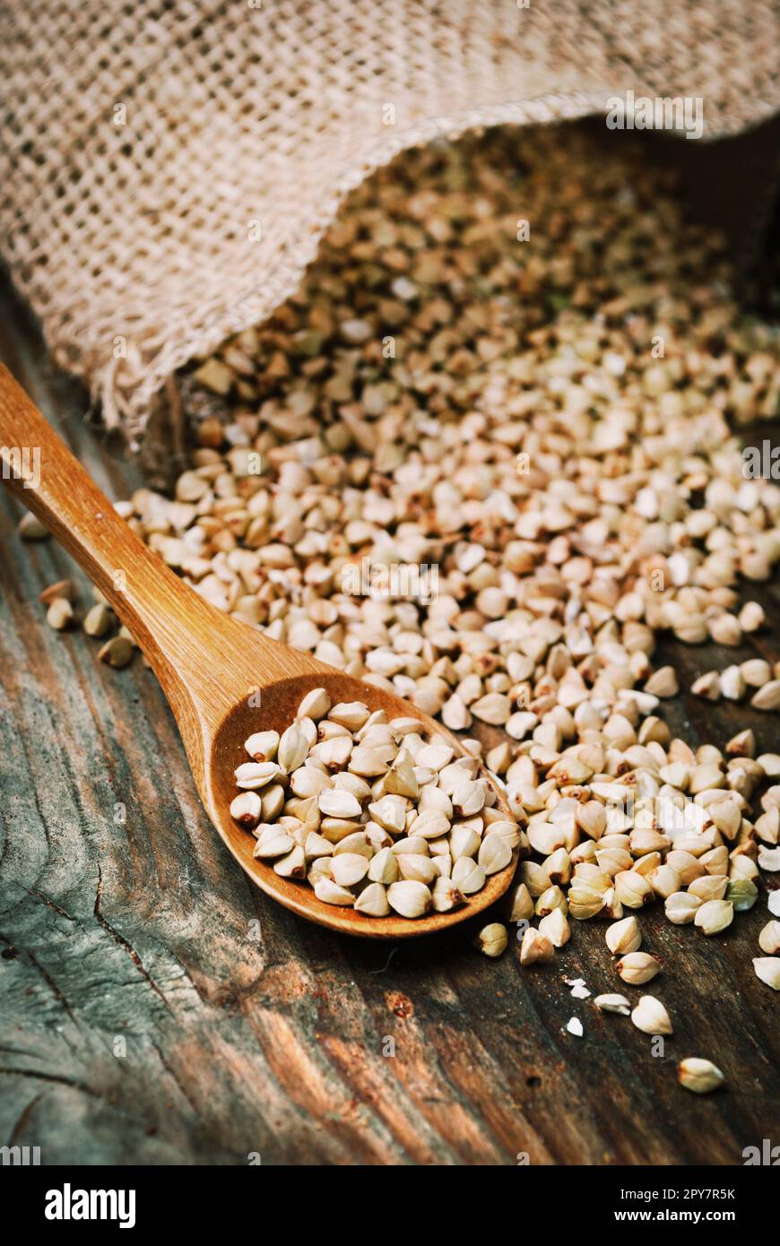 Natura morta con un mucchio di grano saraceno in cucchiaio di legno su fondo di tavola in legno vintage. Foto Stock