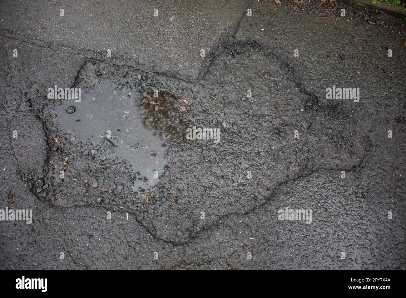 Danni alla strada causati da buche nell'asfalto della carreggiata Foto Stock