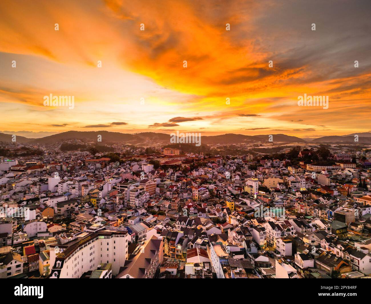 Radioso skyline al tramonto: Accattivante vista del cielo rosso della città di da Lat, Vietnam, con una splendida miscela di colori tra il paesaggio urbano e il cielo al tramonto Foto Stock