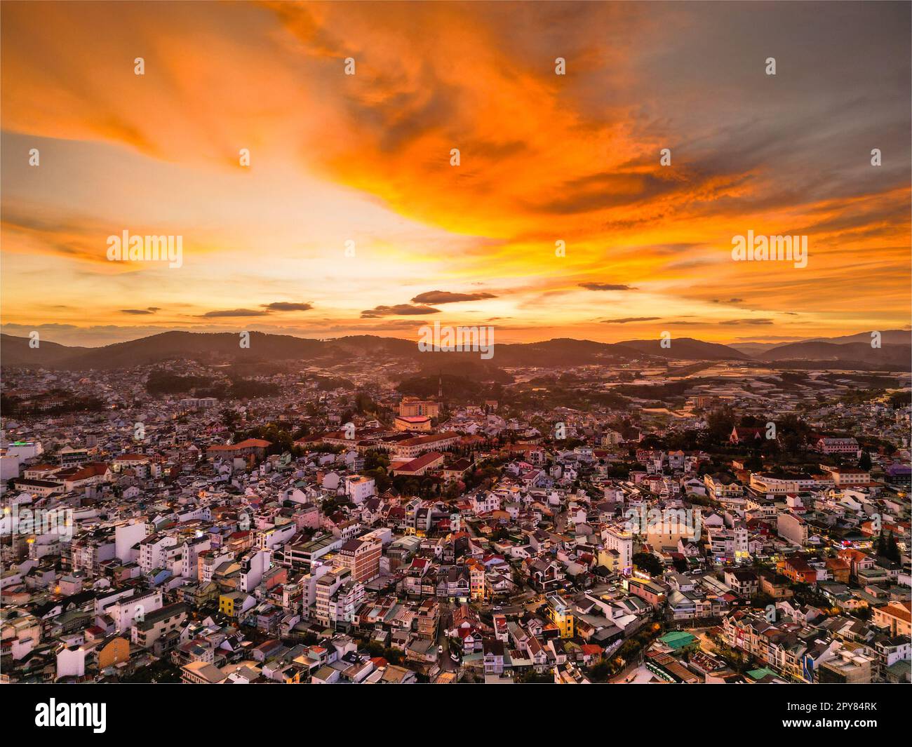 Radioso skyline al tramonto: Accattivante vista del cielo rosso della città di da Lat, Vietnam, con una splendida miscela di colori tra il paesaggio urbano e il cielo al tramonto Foto Stock